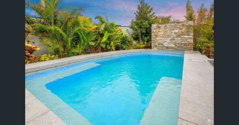 Custom shaped 6.0m x 3.2m concrete pool designed to maximise space along the fenceline. Features a 2m x 1.6m Features a 2.0m x 1.6m Thredbo wall-clad waterfall, Sand Drift Dropface Coping, Salt & Pepper Pebblecrete finish, and frameless glass fencing for an open, modern look.