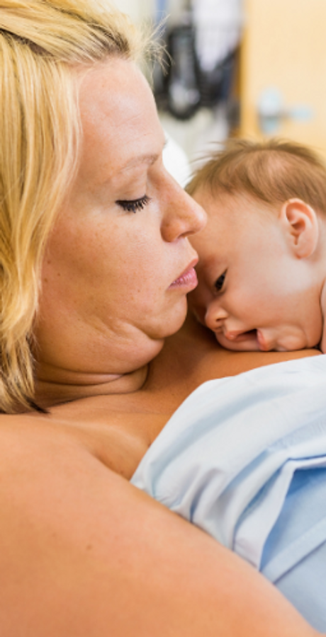 Blonde mom holding baby in hospital bed