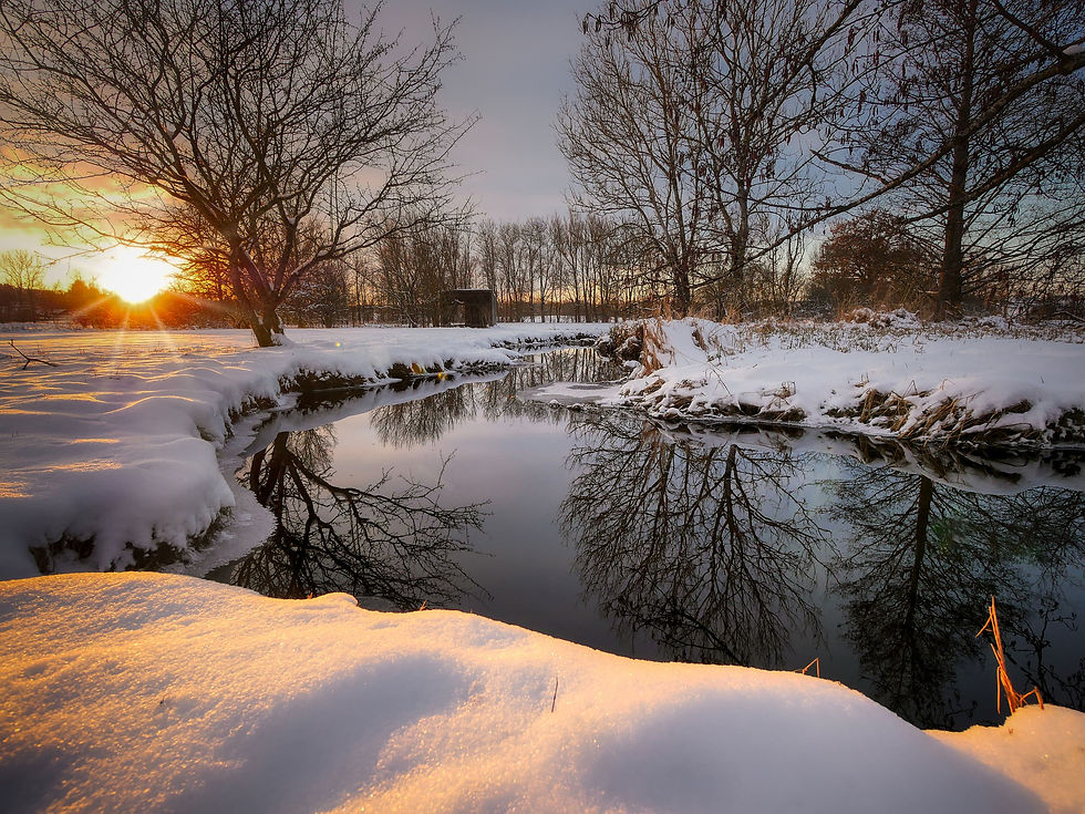 snowy river field landscape with glassy water and colorful sun on horizon