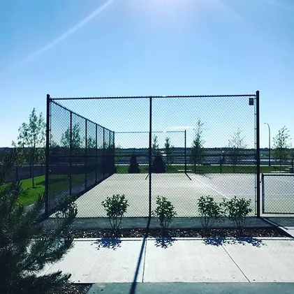 Empty outdoor tennis court with a clear blue sky in the background.