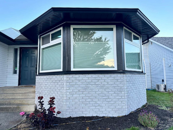 Residential painting of a bay window with black trim and white brick.
