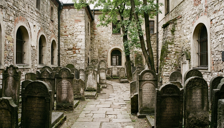 Eye-level view of the Remuh Synagogue courtyard with old gravestones and stone walls.