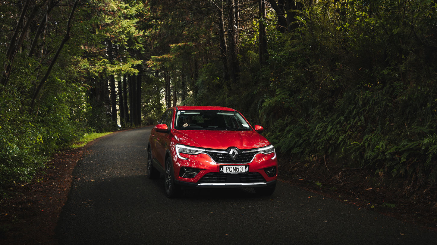 Red 2022 Renault Arkana driving in a forest, near Nelson, New Zealand