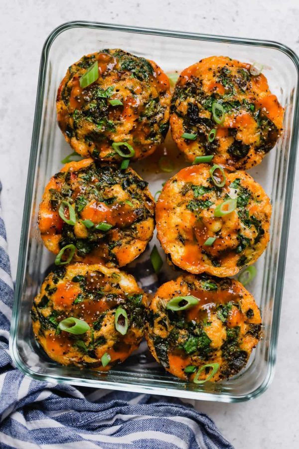 Overhead shot of six Buffalo Chicken Egg Muffins in a clear, rectangular glass storage container.