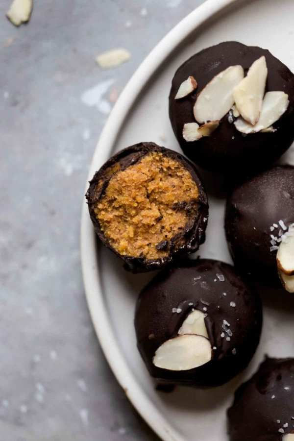 Partial plate shot of chocolate covered pumpkin truffles with one truffle split it half to show center