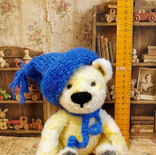 White curly haired bear with blue beanie and scarf.
Movable limbs.