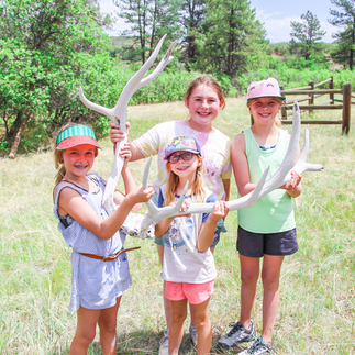 Girls holding an elk antler.