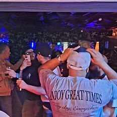 People socializing at The Penguin Room, 'Enjoy Great Times' shirt.