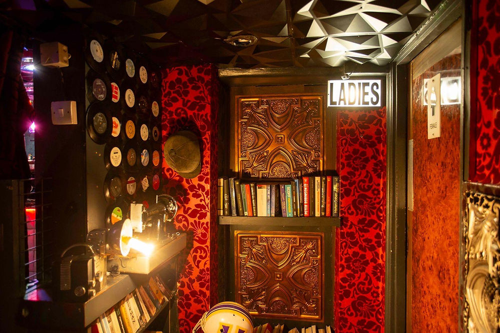 Eclectic red room with records and a 'LADIES' sign