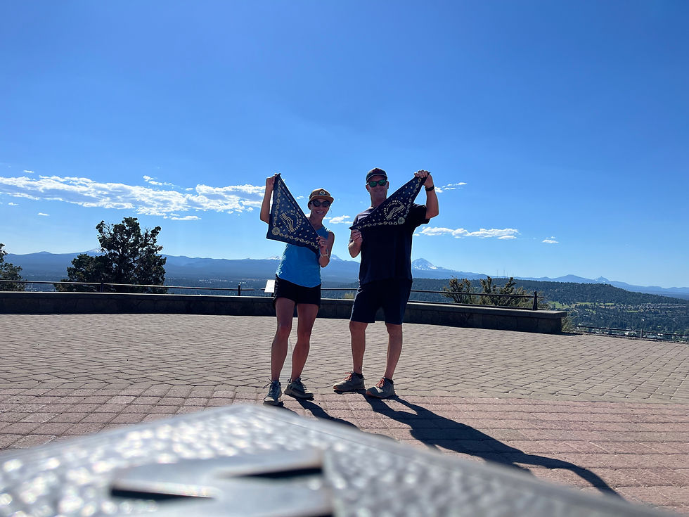 a couple standing at the top of a butte, mountains in background