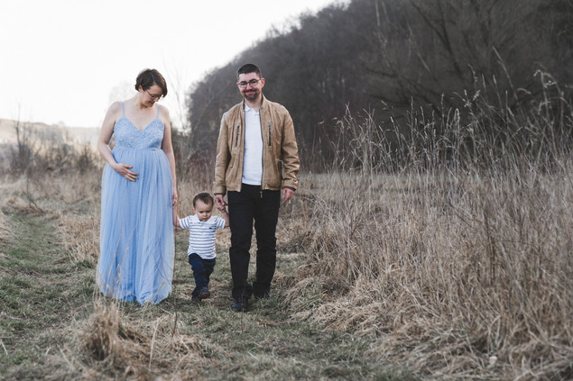 Werdende Mama läuft durch die winterliche Landschaft im Februar, mit einer Hand sanft auf dem Babybauch.