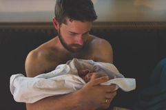 Papa hält sein Baby nach Geburt im Arm