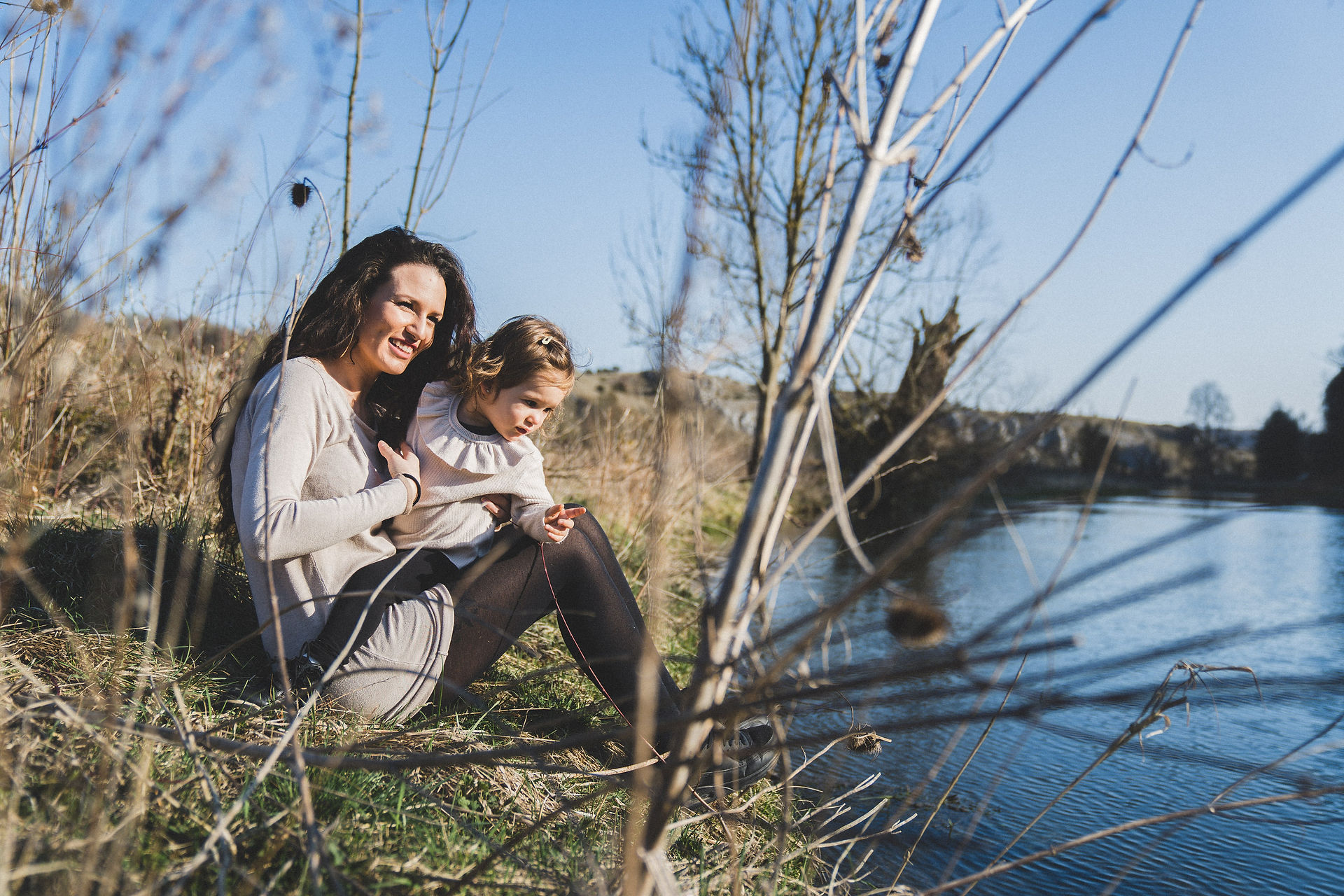 Liebevolle Momente im Winter – Mama und Tochter bei Wintersonne und glitzerndem Wasser der Brenz.