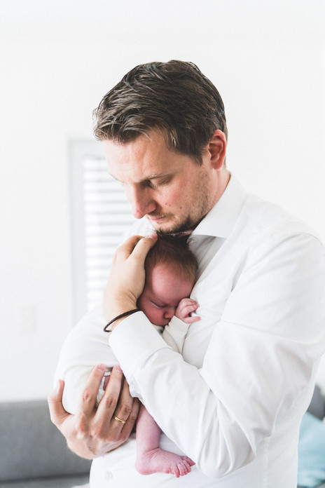 Vater streichelt das Gesicht seines Neugeborenen – intime Familienmomente in Augsburg.