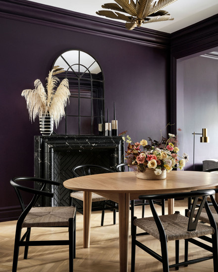 Extendable dining table with black wishbone chairs marble fireplace brass chandelier whimsical quirky moody interiors dark purple