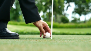 homme en costume sur un green de golf