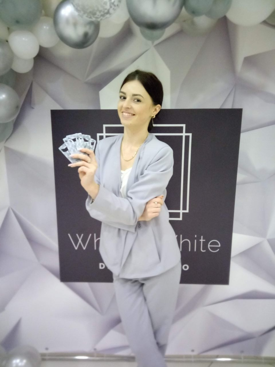 Real photograph showing a person with several HOLDERCARD cards in front of a White&White Dental Studio branded event display