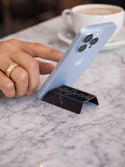 Branded promotional card supporting a smartphone on a café table beside a coffee cup