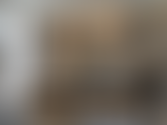 A luxury Miami kitchen designed as a living ecosystem, featuring light oak cabinetry, dramatic marble backsplashes, a sleek black island with organic wooden stools, and floor-to-ceiling windows that invite natural light.