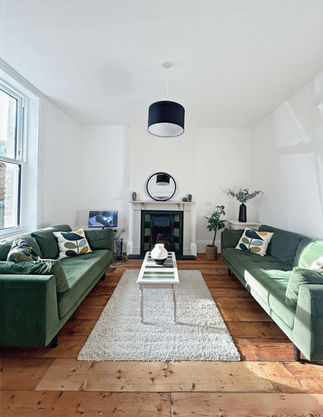Smaller room at the front, which could be used as a study or snug. Shows green sofas and a fireplace in the middle.