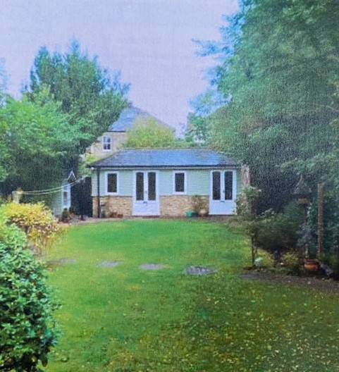 A green lawn with a summer house at the end of the garden.