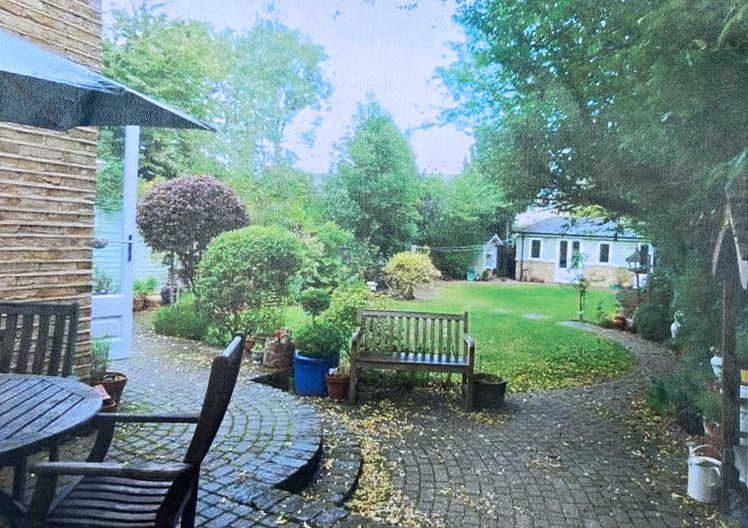 Back garden with a winding cobble path down to a summer house.