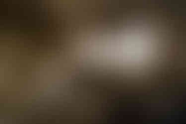 Aragats Scientific Center - Orgov Radio-Optical Telescope. Abandoned room with a decaying ceiling and cracked walls, filled with dirt and debris. Sunlight streams through dusty windows, illuminating scattered triangular glass tiles.