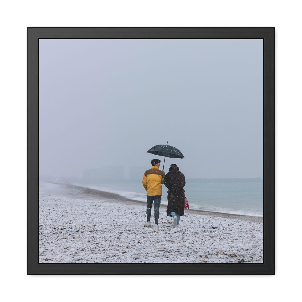 Thumbnail: Two people walk on a snowy beach under an umbrella by the sea.