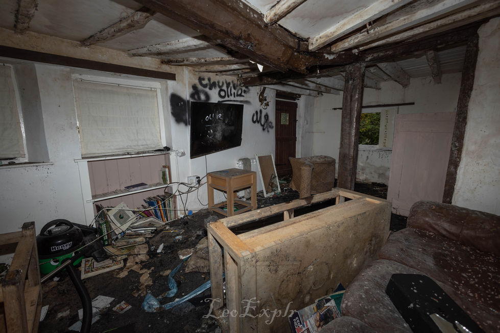 Messy living room in an abanoned home with graffiti on the floor.
