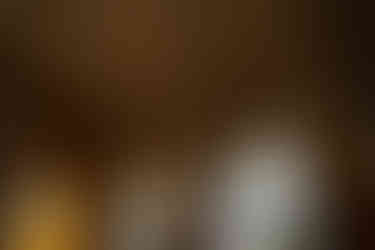 Sanatorium Shakhtar in Tskaltubo, Georgia. Ornate, decaying room with arched windows. Sunlight filters through tattered curtains, casting shadows. Elegant vaulted ceiling, intricate molding.