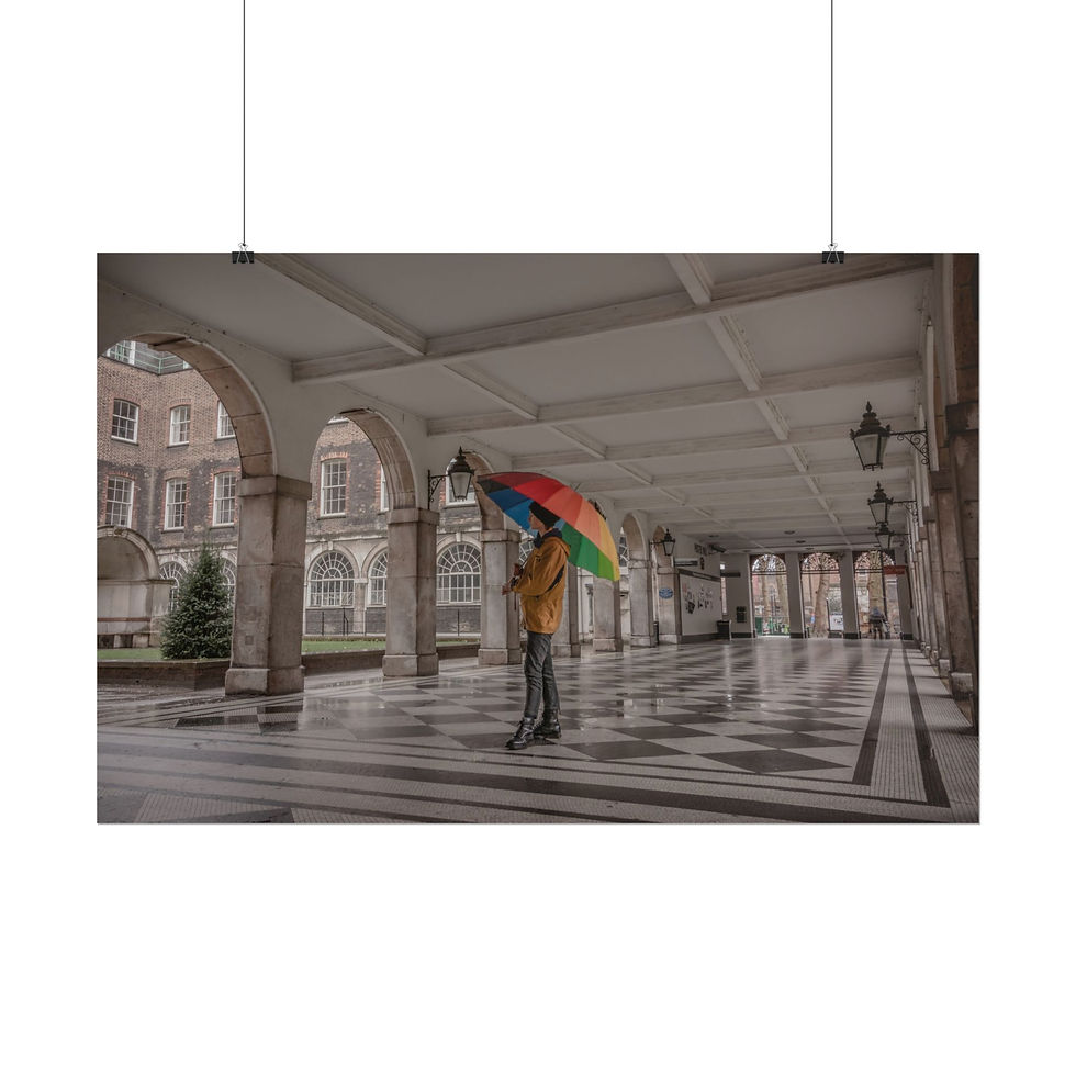 Thumbnail: Person with rainbow umbrella stands under arched walkway in Central London.
