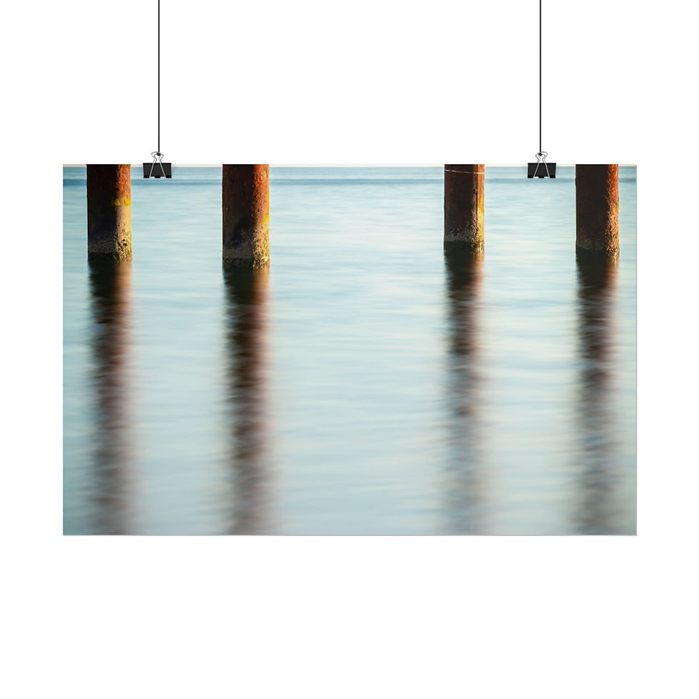 Thumbnail: Four dark pier pilings reflected in tranquil, textured blue water.