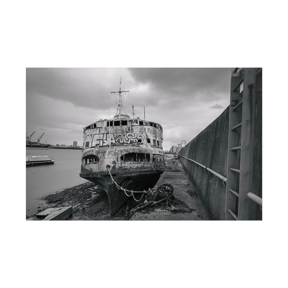 Thumbnail: Derelict ship beached on muddy shore under cloudy sky, black and white.