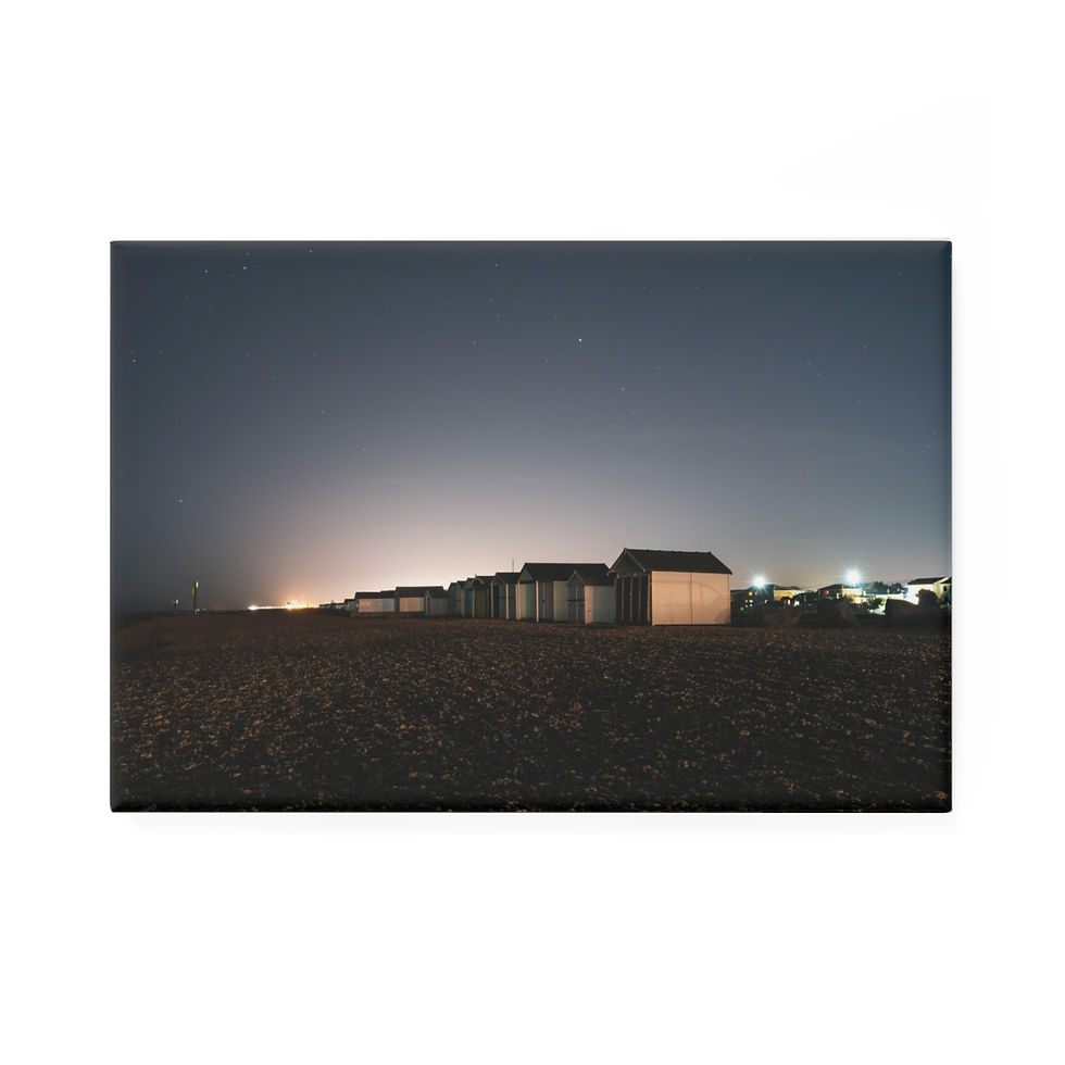 Thumbnail: Row of beach huts under a dark night sky with distant lights.