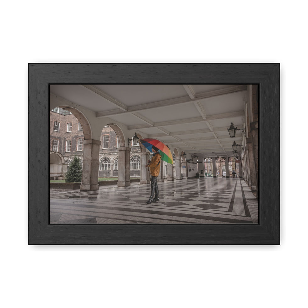 Thumbnail: Person with rainbow umbrella under arches in a long, sunlit corridor.