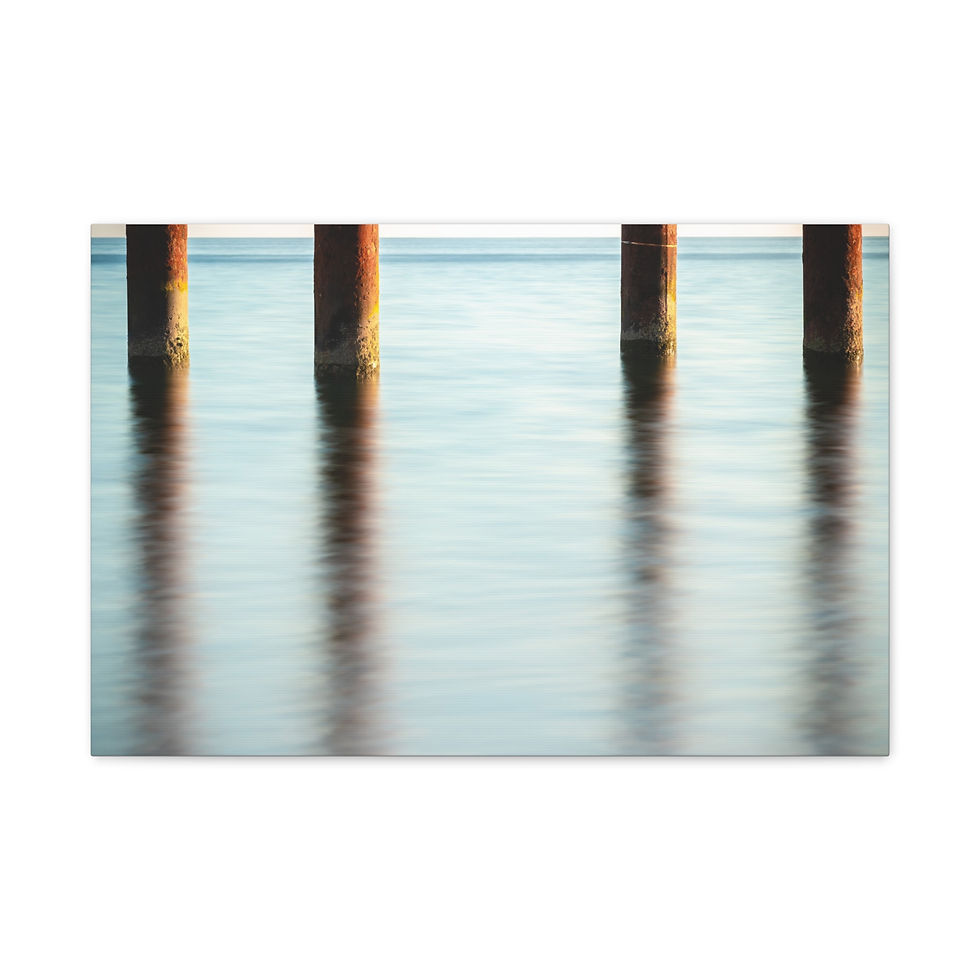 Thumbnail: Four weathered pilings stand in calm water with long, clear reflections.
