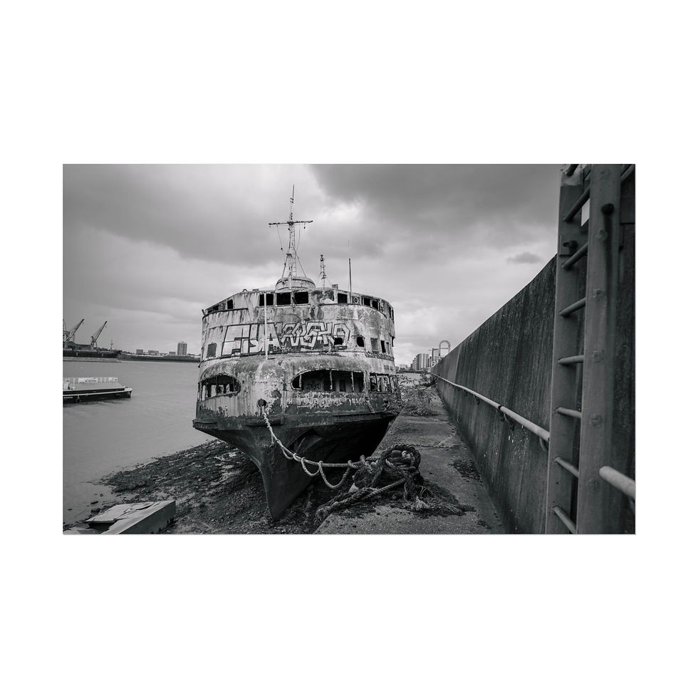 Thumbnail: Grayscale view of rusty, abandoned ship beached on a muddy riverbank.