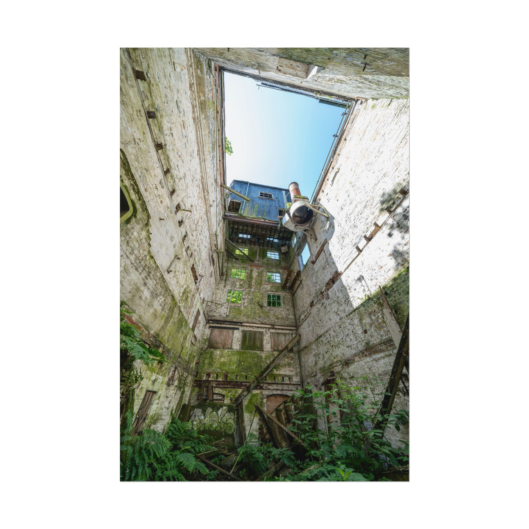 Derelict building interior looking up at sky through missing roof.