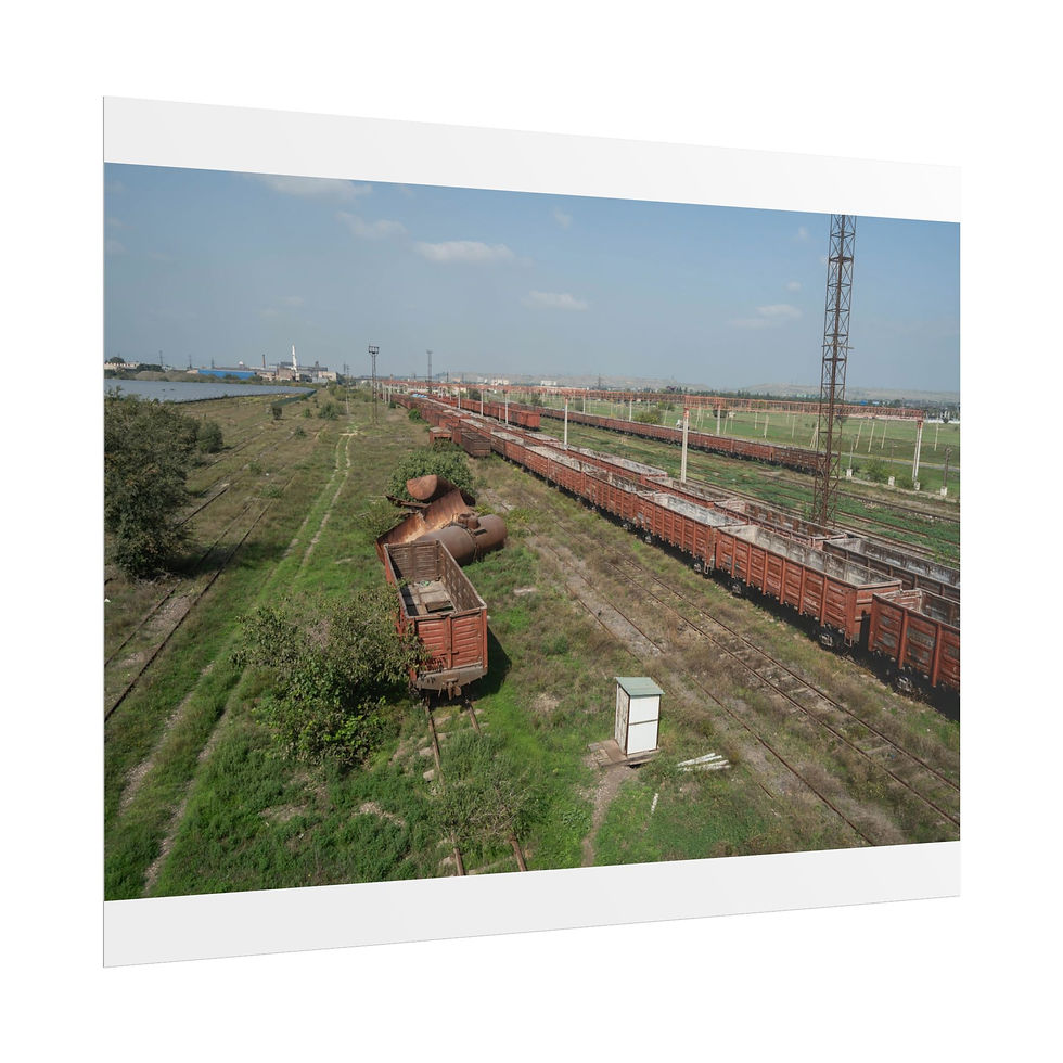 Thumbnail: Cargo trains on tracks in a grassy industrial area under blue sky.