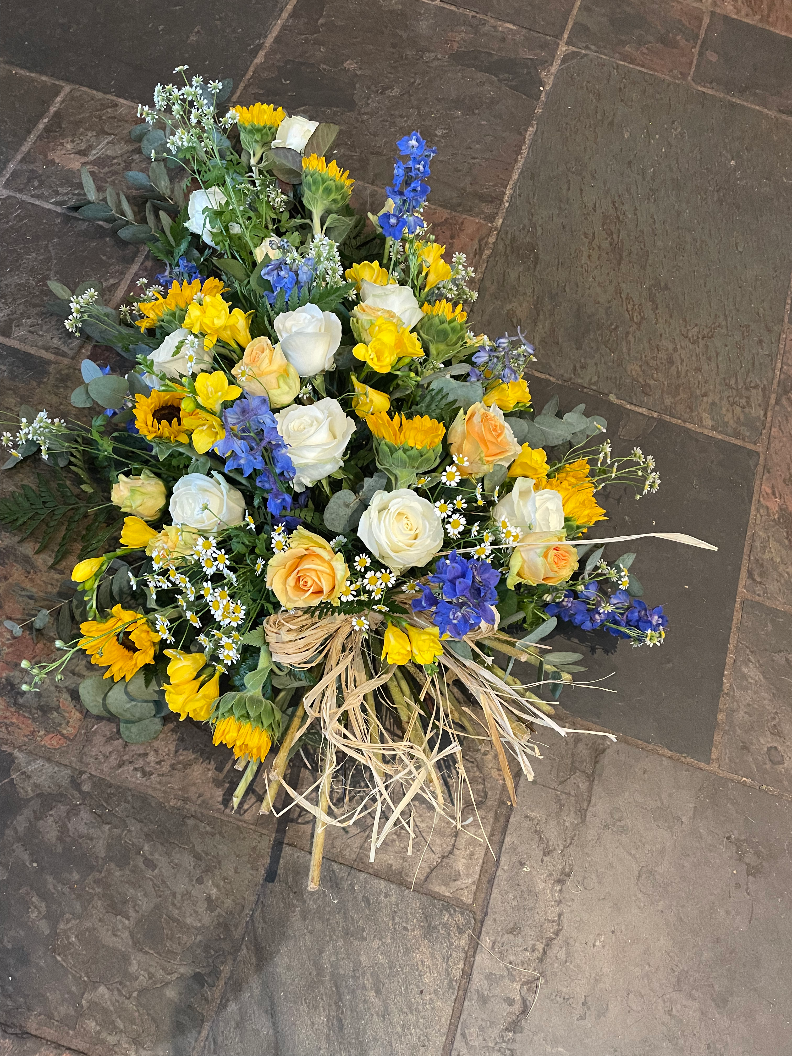 Floral tribute: sunflowers, roses, delphiniums, tied sheaf