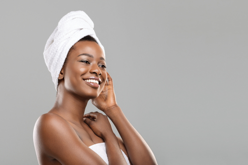 Smiling woman on the left side with glowing skin and a towel wrapped around her head, gently touching her face - representing skincare expectations. On the right side, a woman is examining her face in the mirror with a concerned expression - representing the reality of skincare results.