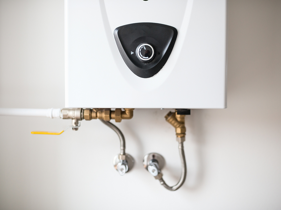 White wall-mounted water heater with black control knob, brass pipes, and valves against a plain light wall.