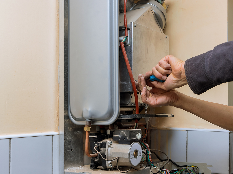 Hands use a screwdriver to repair the inside of a wall-mounted boiler, with wiring and metal parts exposed in a utility room