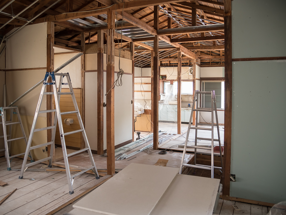 Construction site with wooden frames and ladders in a partially built interior. Exposed beams and wires suggest ongoing renovation.