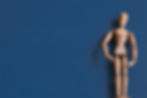 la-statuina-di-legno-su-una-superficie-blu.jpg