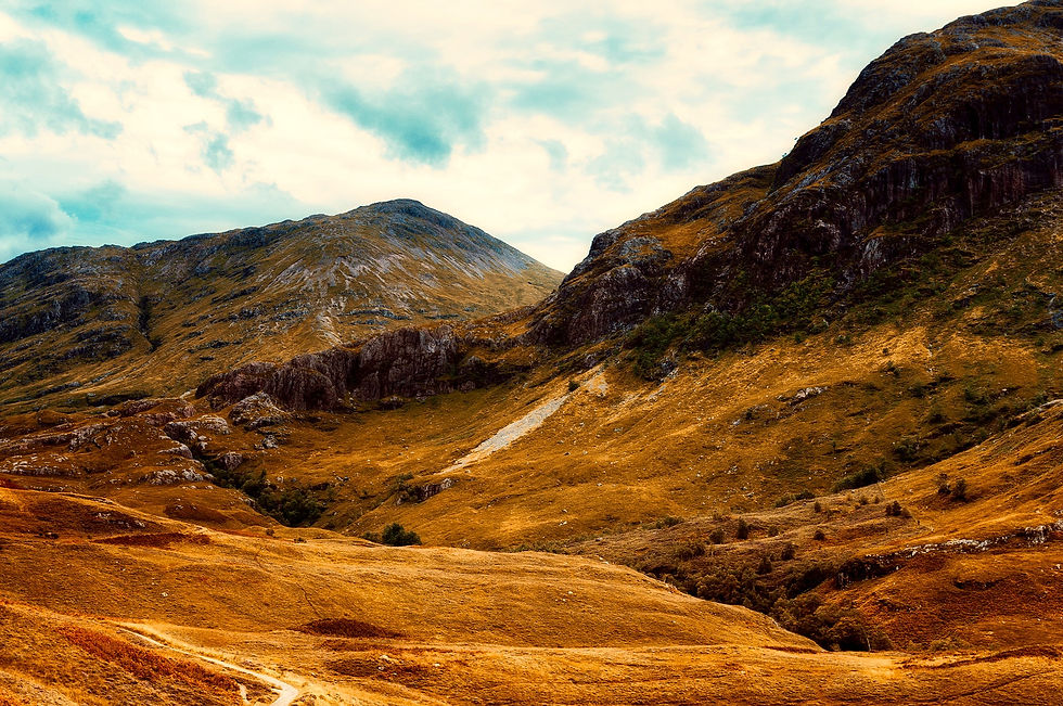 A beautiful photograph of some Scottish mountains in Autumn covered in golds, oranges, yellows, muted greens, and the hint of stone peaking out of the grassy blankets.