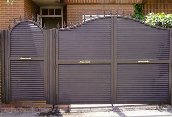 Puerta de forja en la fachada con ornamentaciones clásicas en la parte superior.