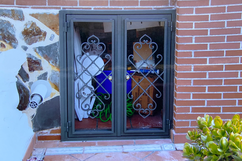 Puerta de trampilla forjada con adornos metálicos en el sótano.