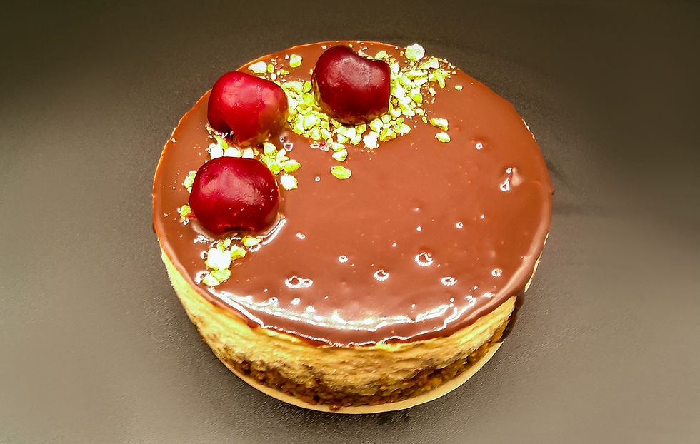 Cheesecake with cherries, pistachio crumbs, and dark chocolate ganache.