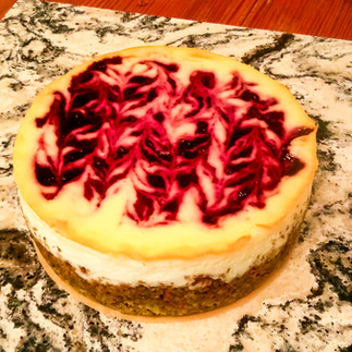 A cheesecake with cherry swirl on top.